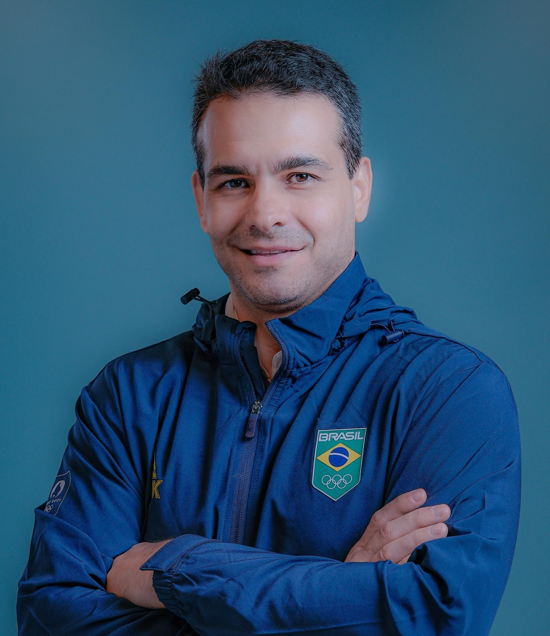 Guilheiro é moreno e branco e está de casaco azul do Brasil, de braços cruzados