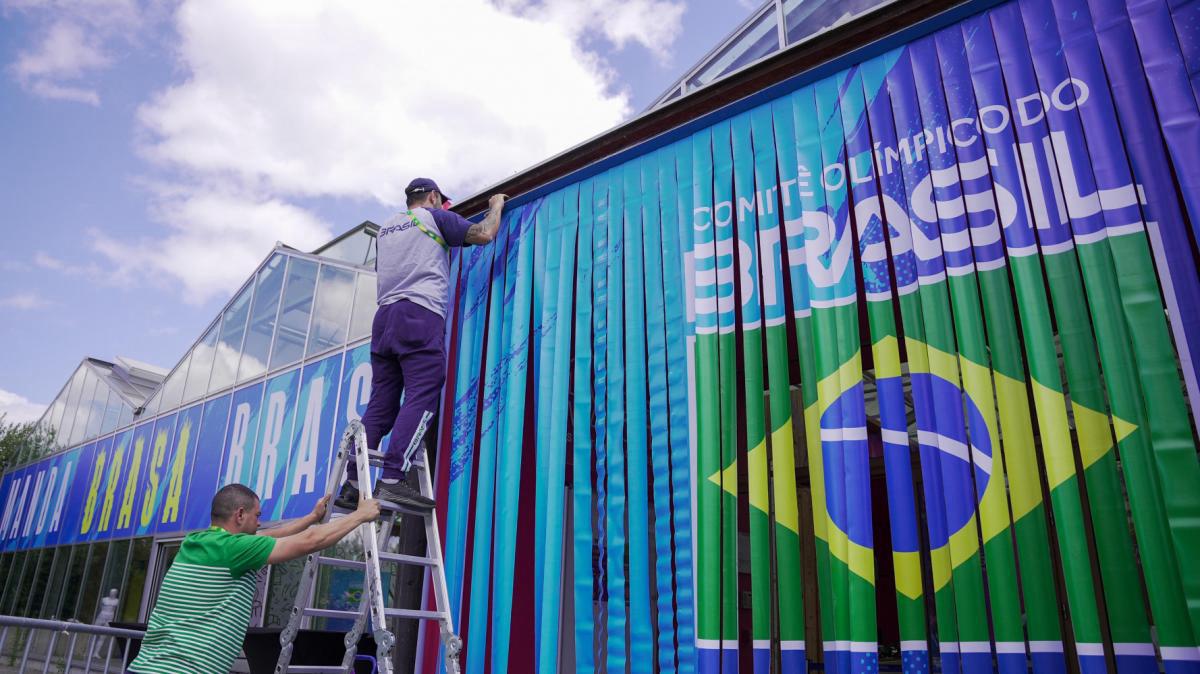 Trabalhadores instalam itens com a identidade visual do Time Brasil